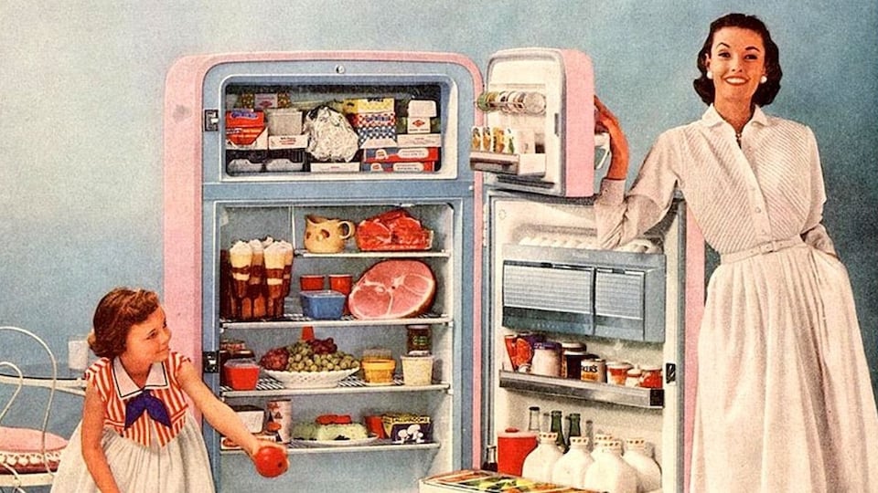 Une femme montre le contenu de son réfrigérateur dans une publicité des années 1950.