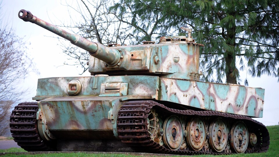 Un char d'assaut allemand de modèle tigre, immobile sur une pelouse devant un arbre.