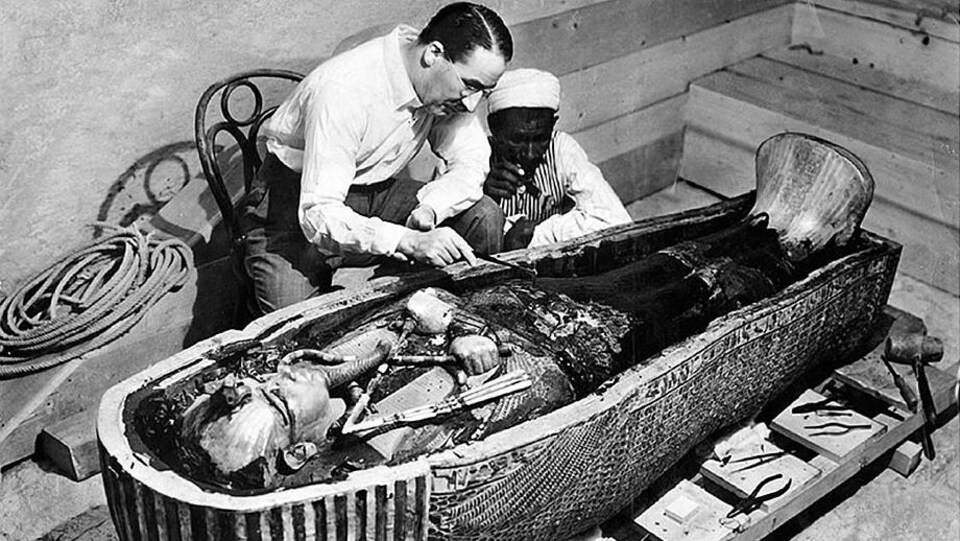 Deux hommes observent attentivement une tombe égyptienne antique.