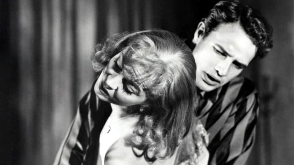 En noir et blanc, un homme (Marlon Brando) tient dans ses bras une femme (Vivien Leigh) qui veut s'enfuir.