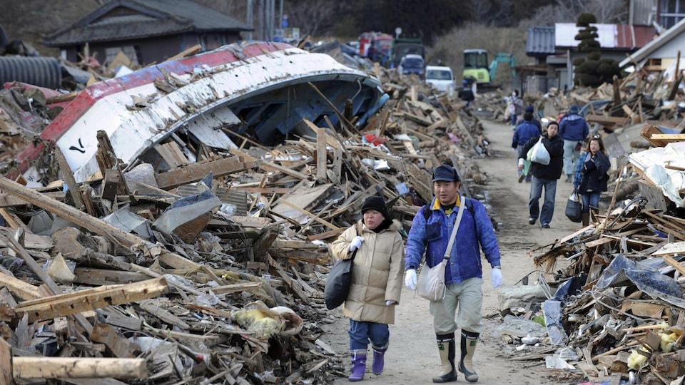 Des résidents de Minamisanriku marchent à travers les décombres laissés par le tsunami du 11 mars 2011.