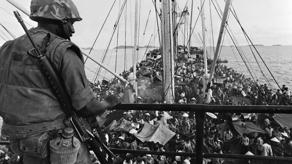 Un soldat regarde des personnes entassés dans un navire.