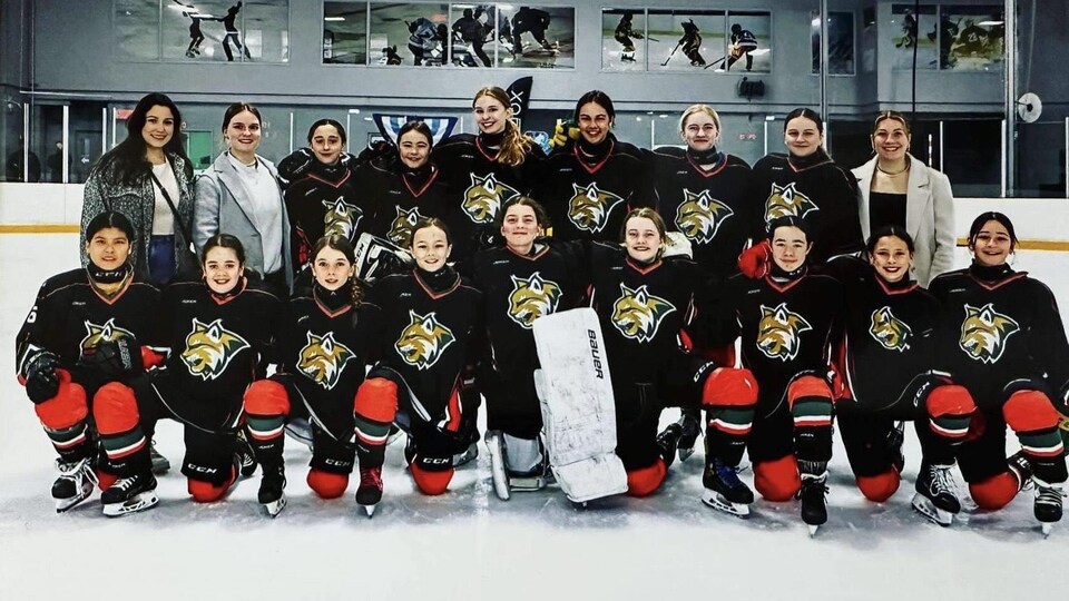 Une équipe de hockey féminine pose sur la glace.