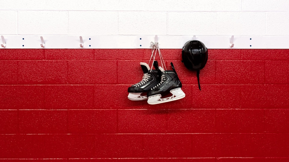 Des patins sont accrochés sur le mur d'un aréna.