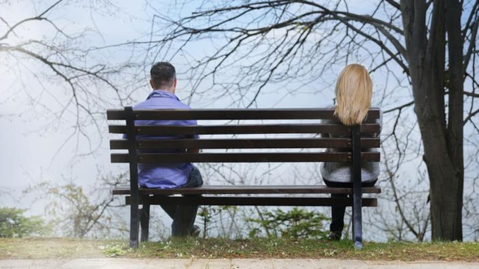 Un couple éloigné sur un même banc.