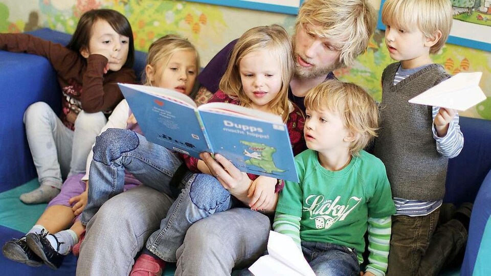 Un homme lit une histoire à des enfants dans un centre de la petite enfance.