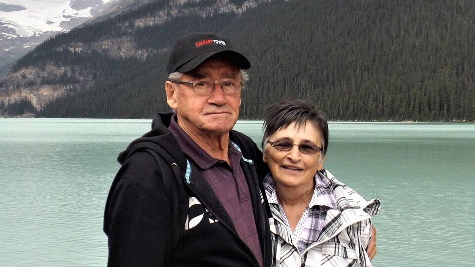 Portait du couple devant de grandes montagnes et un lac.