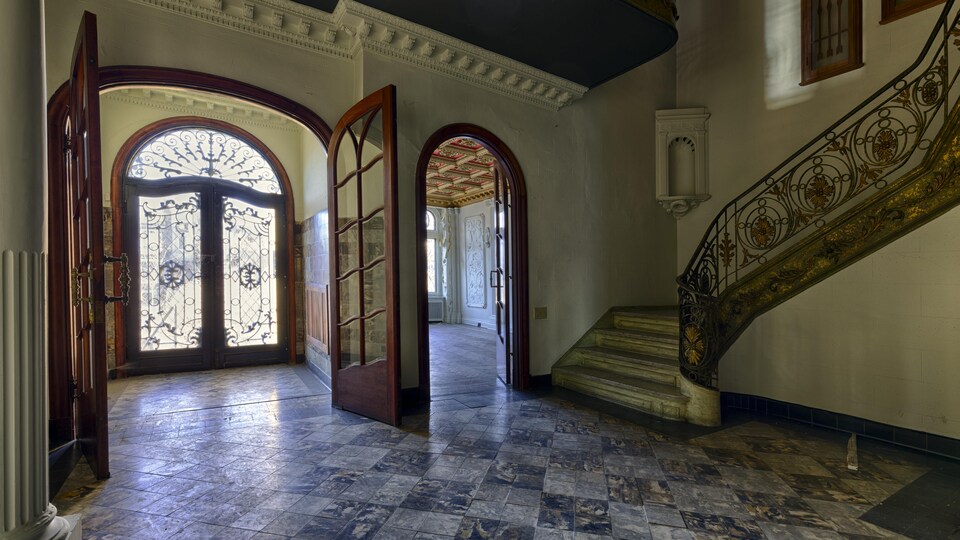Une entrée de maison lumineuse avec de grandes portes vitrées et des sculptures de fer.