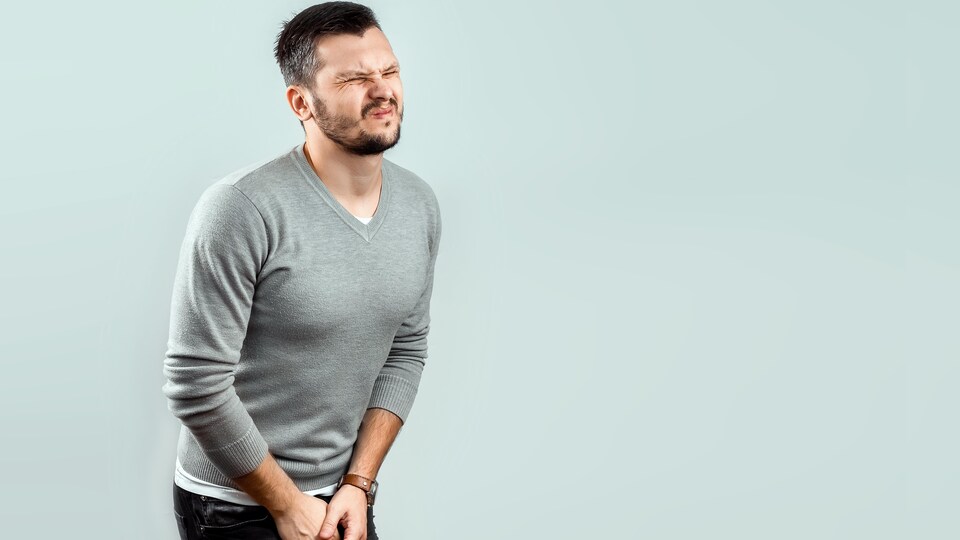 Un homme qui se tient la vessie et qui semble souffrir.