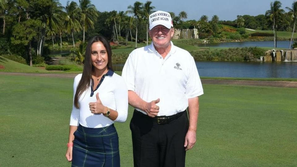 Une femme et un homme sourient et montrent un pouce en l'air sur un terrain de golf. 