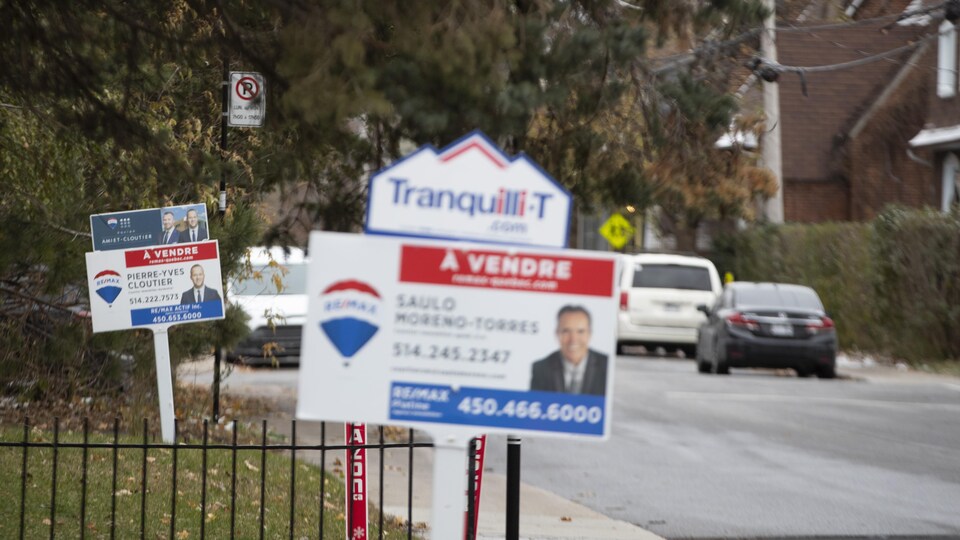 Deux pancartes de maison à vendre sur une rue en banlieue de Montréal. 