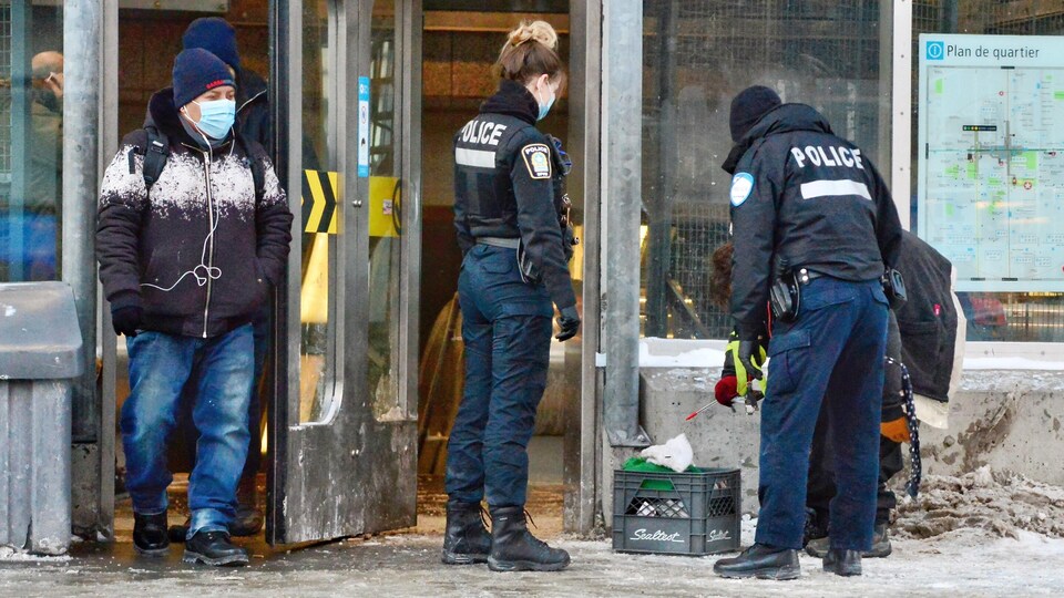 Des agents du Service de police de la Ville de Montréal interviennent auprès d'un itinérant à la station de métro Berri-UQAM.