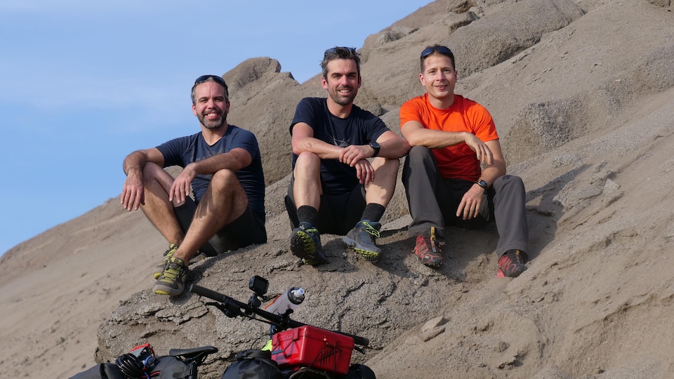 Jacob Racine,Daniel Barriault et Frederic Dion assis sur un rocher en Amérique du Sud.