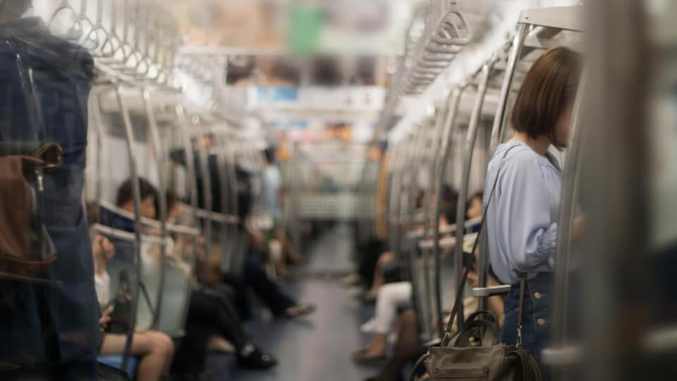Des hommes et des femmes, photographiés de manière floue, dans une rame de métro.