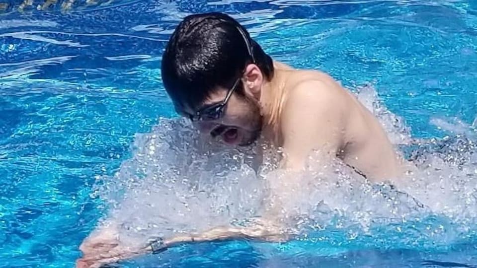 Il nage dans une piscine avec ses lunettes de plongée.