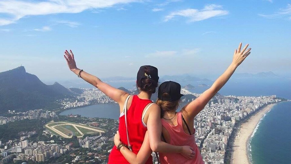 Deux femmes font dos à la caméra en regardant le paysage du sommet de la colline.