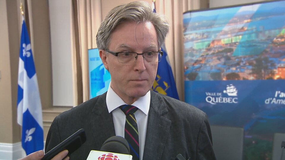 Jean Rousseau répond aux journalistes dans une salle d'audience.