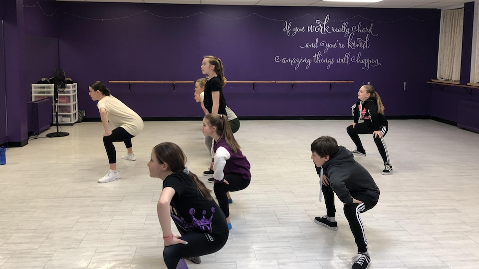 Des enfants et leur enseignante de danse lors d'un cours dans un studio de danse.