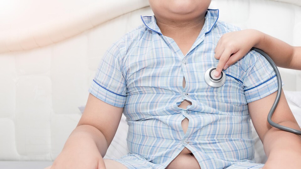 Un médecin avec un stéthoscope écoute le coeur d'un jeune garçon.