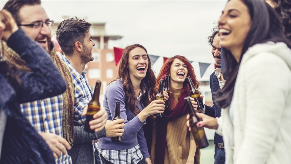 Des jeunes adultes consomment de la bière en bouteille.