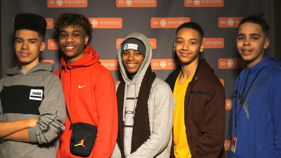 Les cinq jeunes devant le mur aux logos d'ICI Première.