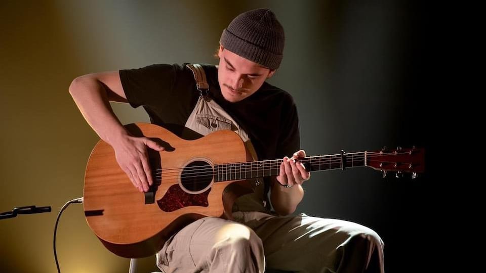 L'homme joue de la guitare sur une scène.