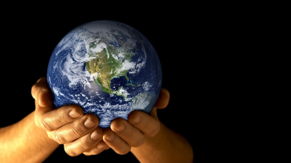 Une personne tient une réplique de la planète Terre dans ses mains.