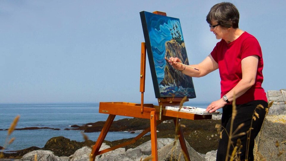 June Deveau peint devant la mer.