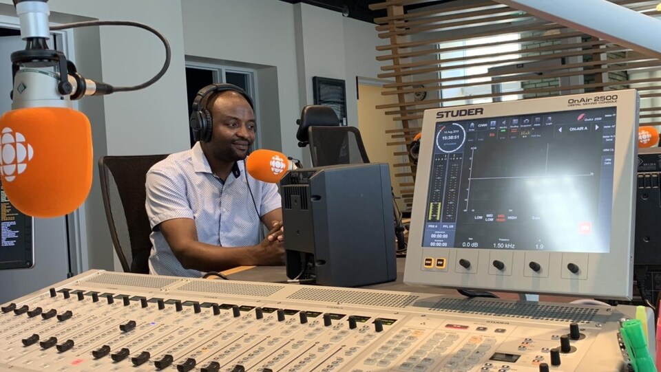 Un homme assis parle à un micro de radio.