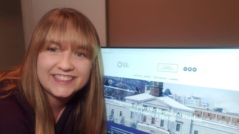 Une jeune femme sourit devant son ordinateur