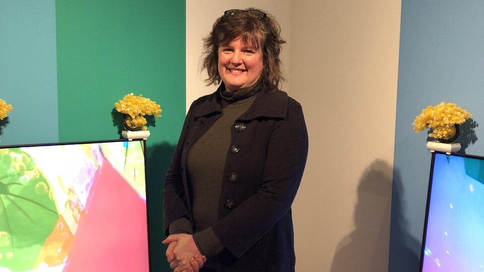 Kate Wolforth debout devant des oeuvres d'arts