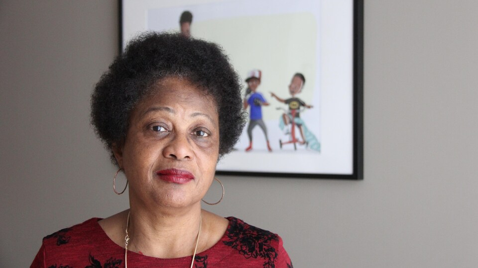 Une femme de la communauté noire de Montréal prend la pose devant un tableau montrant des enfants. 