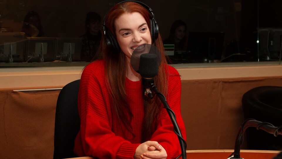 La jeune danseuse porte les cheveux rouges et un pull rouge.