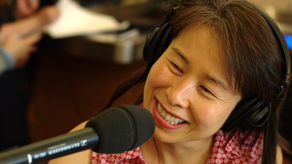 Kim Thúy, tout sourire, derrière un micro