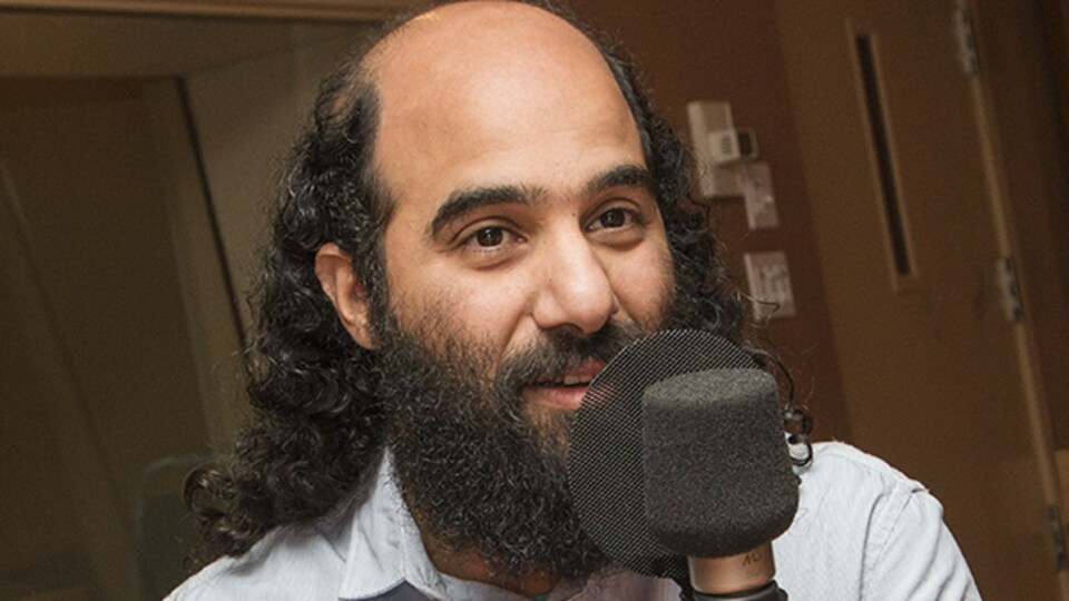 Un homme est photographié dans un studio de radio, devant un micro.