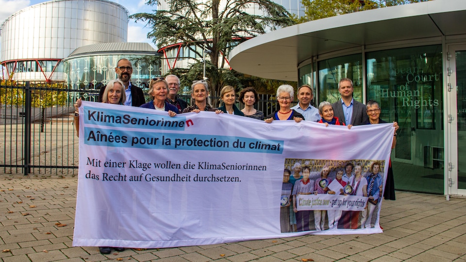Des femmes âgées tiennent une banderole représentant leur groupe devant la Cour européenne des droits de l'Homme. 