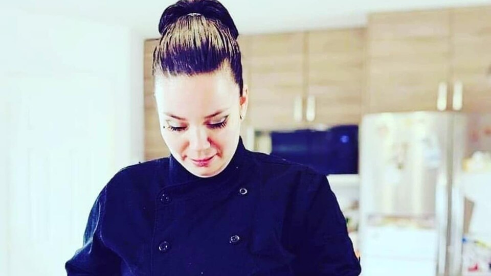 Krystle Rosalie Regis, chef cuisinière, dans une cuisine, coupant des légumes sur le comptoir.