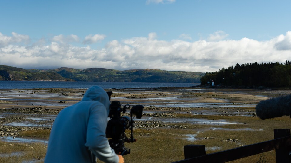 Un cameraman film un paysage de mer et montagne