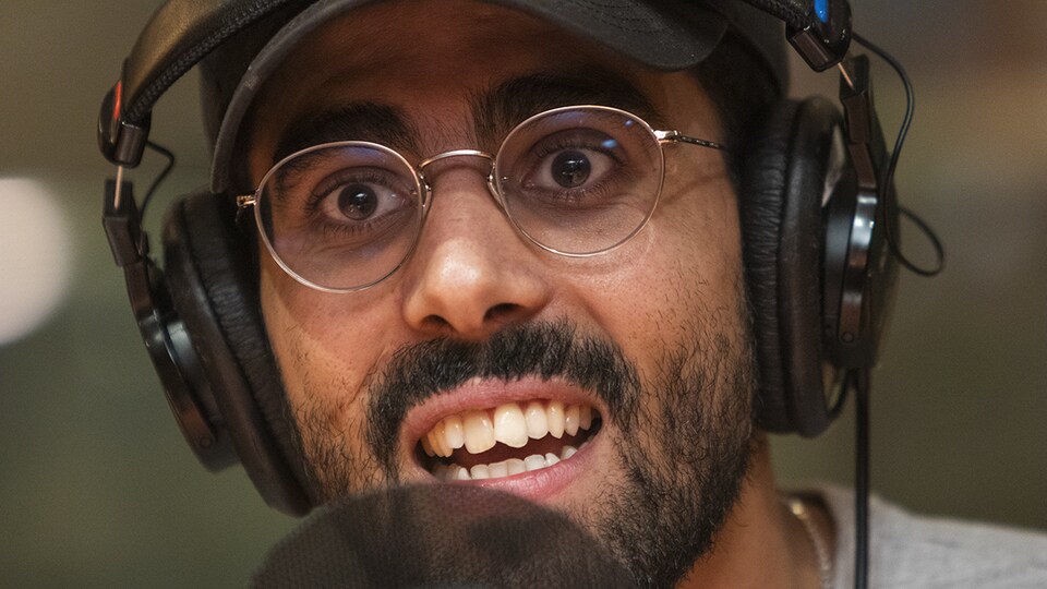 Captivé, Adib Alkhalidey répond à une question derrière un micro d'ICI Première.