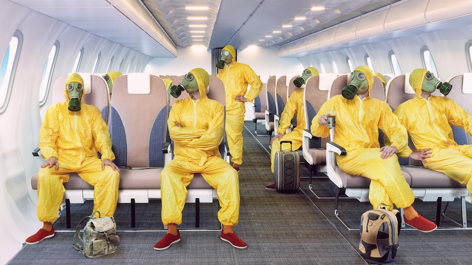 Des passagers portant des masques à gaz assis à l'intérieur d'un avion.
