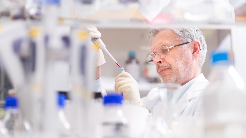 Un scientifique prélève un échantillon dans une éprouvette.