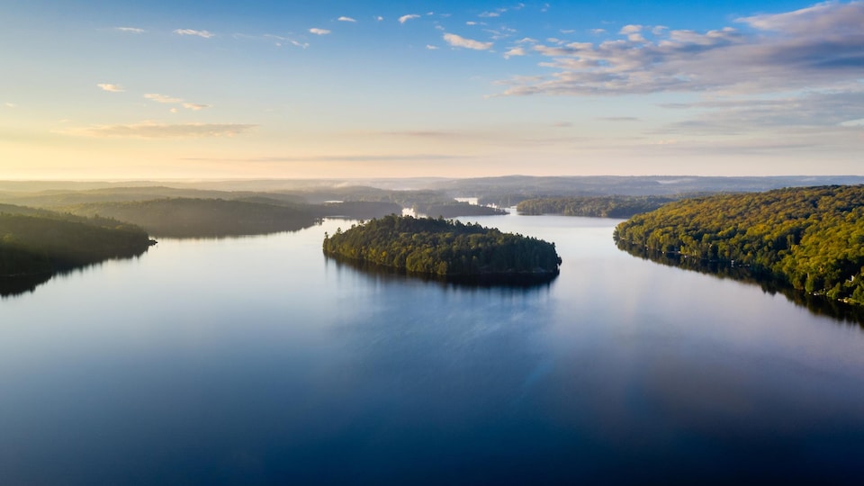 Vue aérienne d'un lac entouré de forêt.