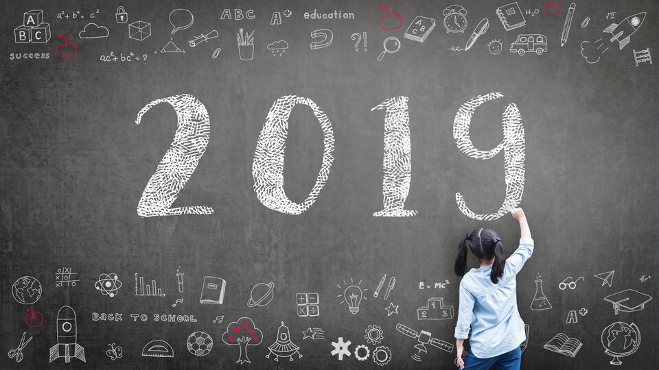Une fillette devant un tableau noir sur lequel il est inscrit le chiffre 2019.