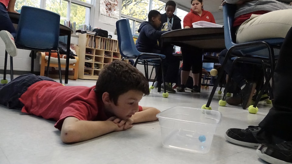 Un garçon couché sur le plancher de la classe participe à l'expérience scientifique.