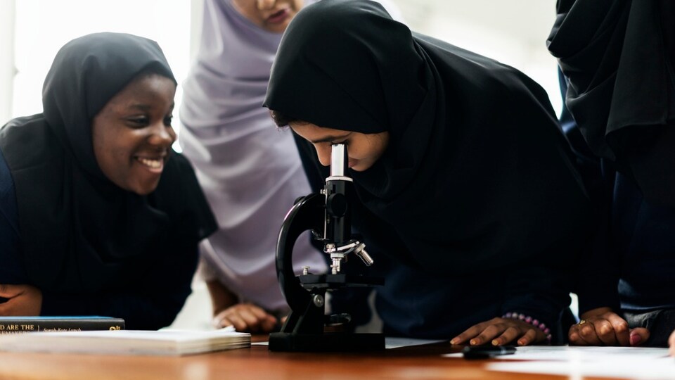 Deux étudiantes regardent dans un microscope.