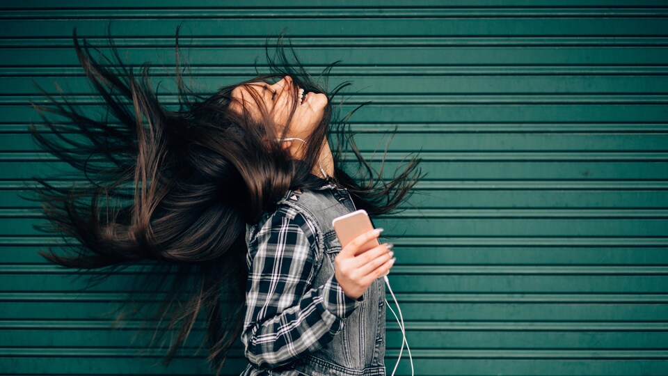 Jeune femme qui écoute de la musique, cheveux au vent.