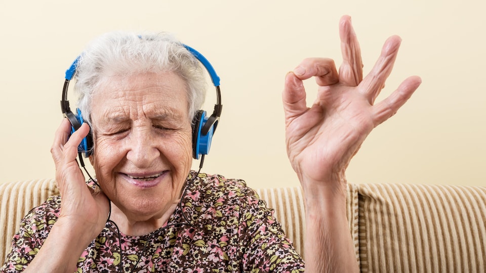 Une dame agée qui écoute de la musique avec un sourire au visage.