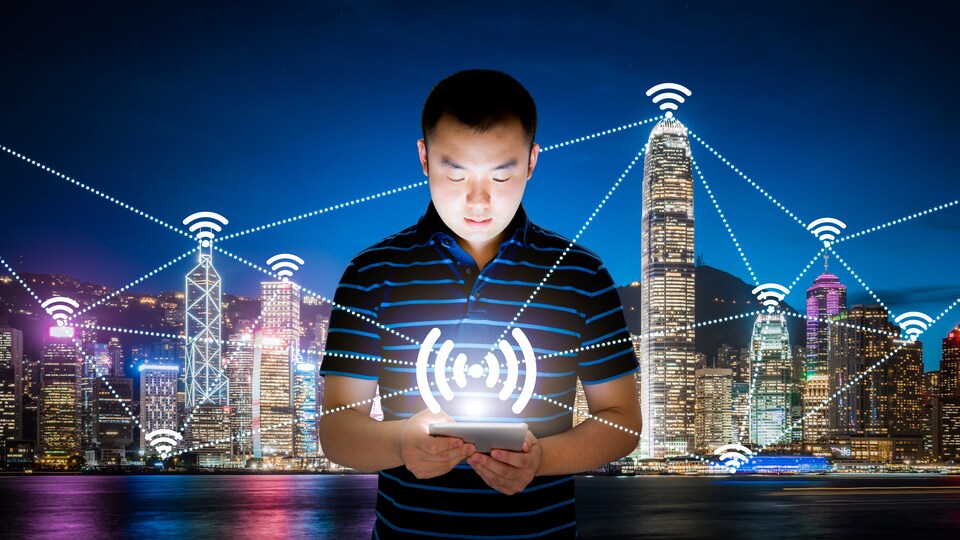 Un homme utilise une tablette devant un arrière-plan représentant une ville intelligente.