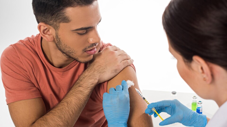 Un patient reçoit une injection sur le bras.