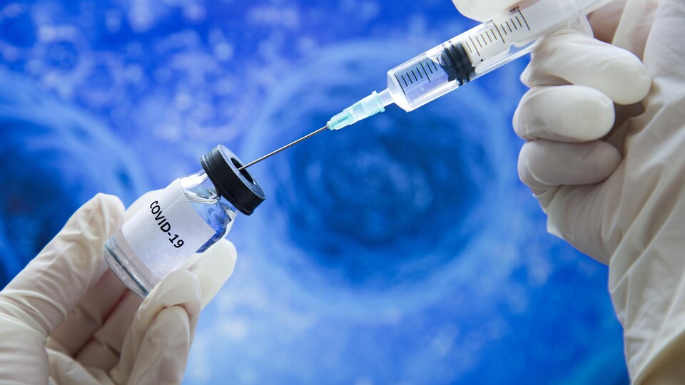Une dose de vaccin est prélevée dans un fiole à l'aide d'une seringue.